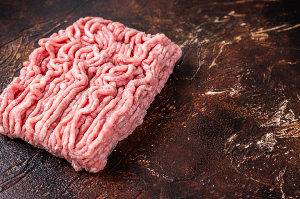 istock Raw ground chicken or turkey meat on brown table. Dark background. Top View. Copy space 1340115354