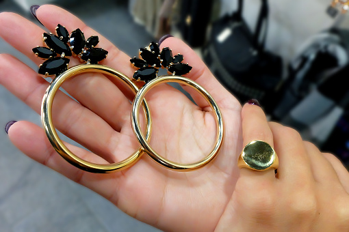 Set of golden earrings and ring on female hand