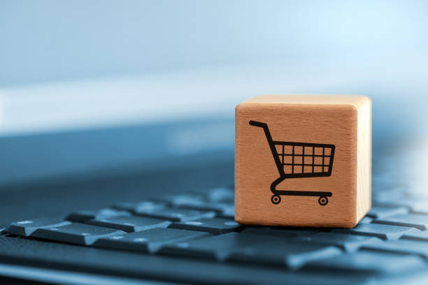 cube with shopping trolley symbol on the laptop keyboard - e commerce imagens e fotografias de stock