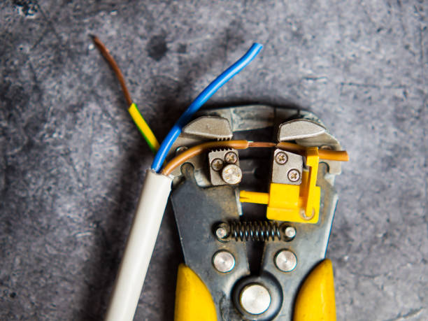 An electrician strips electrical wires with a stripper. An electrician strips electrical wires with a stripper. wire cutter stock pictures, royalty-free photos & images