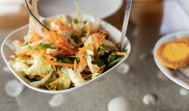 istock She is mixing the salad with his fork and knife. 1340120696
