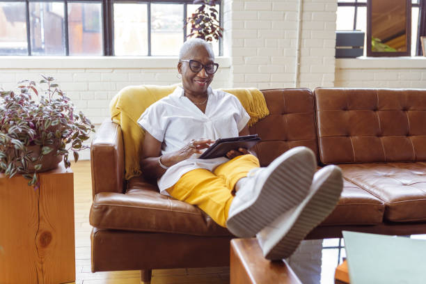 istock Senior businesswoman working on tablet computer from sofa at home 1340124917