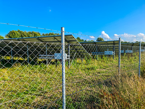 Generating clean energy with solar modules in a big park in northern Europe. Close up with fence