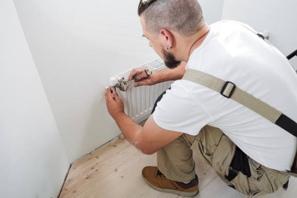 istock Plumber installing new steel hot water central heating radiator 1340132697