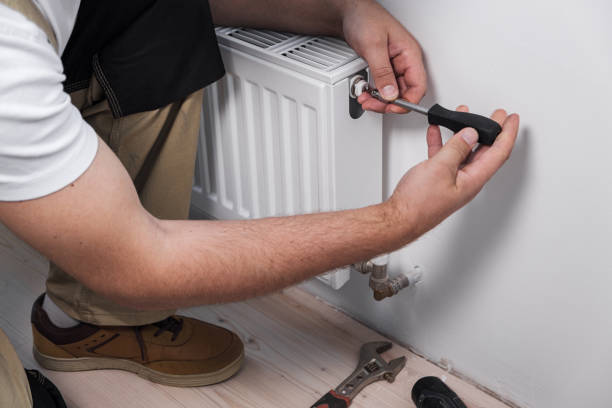 istock Plumber installing new steel hot water central heating radiator 1340132711