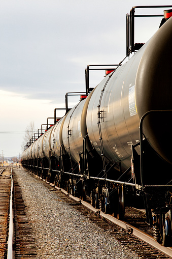 A line of black railroad tanker cars on the tracks waiting to be filled.