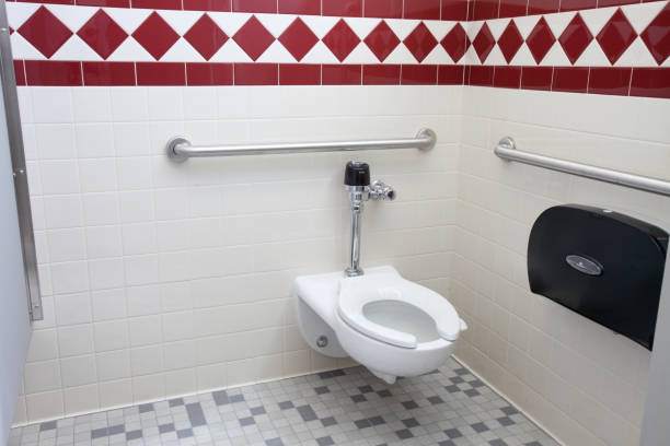 Handicapped accessible water conserving toilet A handicapped accessible toilet in a handicapped accessible stall with safety bars flushing valve public restroom toilet stock pictures, royalty-free photos & images