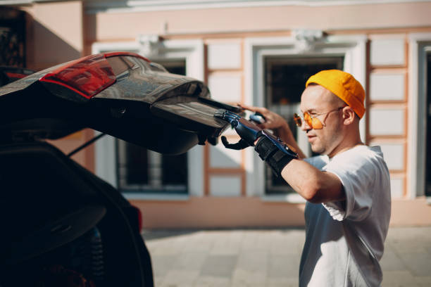 istock Young disabled man with artificial prosthetic hand closing back trunk of car 1340144443