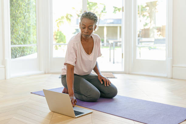 mujer negra jubilada activa haciendo clases de yoga en línea en casa - women yoga yoga class mature adult fotografías e imágenes de stock
