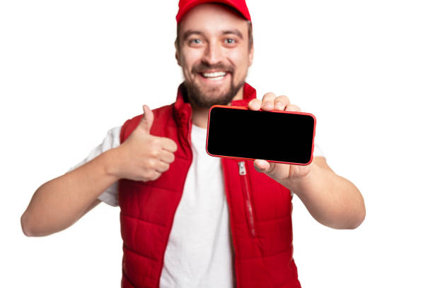 istock Cheerful delivery man recommending app on smartphone 1340145464