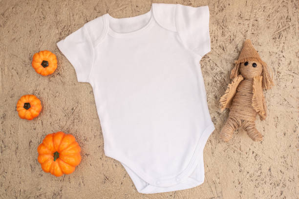 istock White baby bodysuit mockup with halloween decor on gold 1340148059