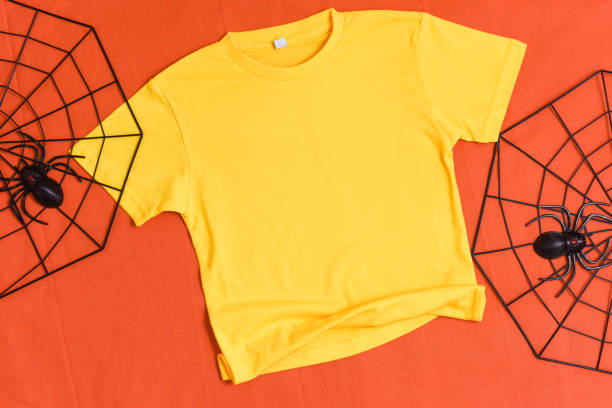 istock Yellow t-shirt mockup with halloween spiderweb decor on orange background 1340148094