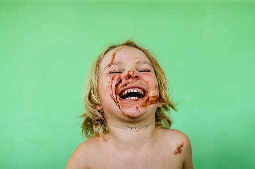 A small boy laughs unabashedly with chocolate all over his face