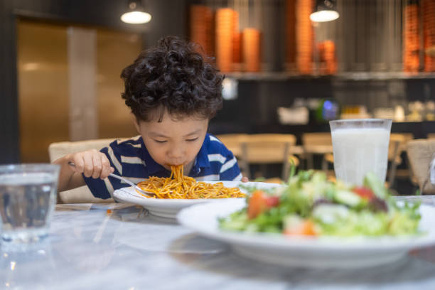 istock A little boy eating pasta in a restaurant 1340155112