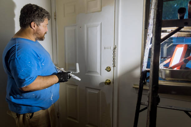 istock Close up of painter hands with gloves painting the door frame using hand roller 1340157627