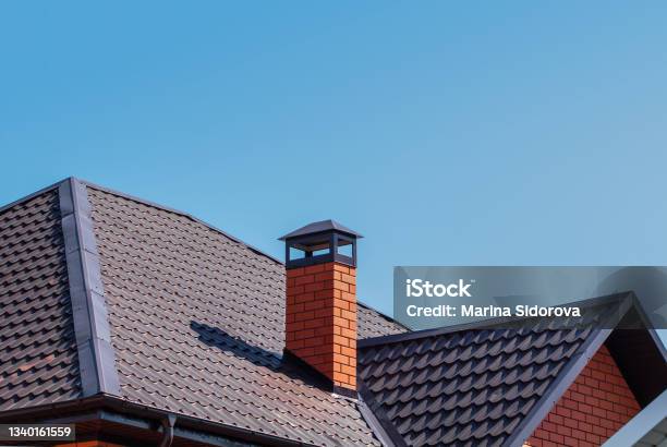 Brick Chimney Pipe On Metal Roof Of A Private House Against The Sky Stock Photo - Download Image Now
