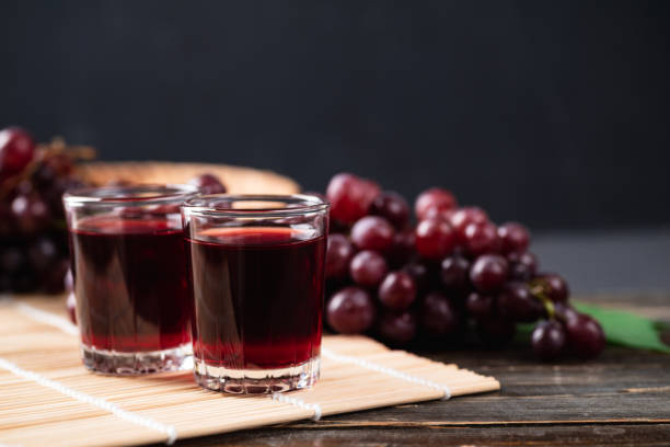 istock Red grape juice in a glass with fresh grape on wooden background 1340164152