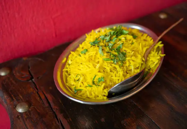 Photo of An Indian style yellow rice in bowl and served on table.