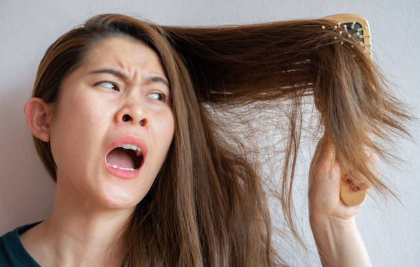istock Funny Asian woman having problem of her thick hair while using hair brush. 1340165988
