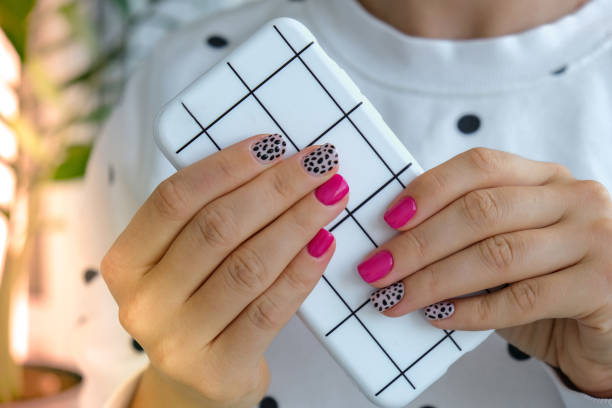 istock Manicured female hands with stylish pink nails holding mobile phone. Smartphone technology. Trendy modern design manicure. Gel nails. Skin care. Beauty treatment. Nail care. Trendy colors 1340170603