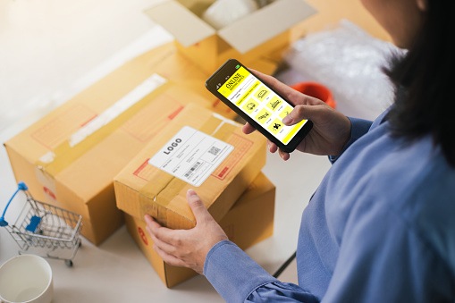 Business woman management parcel with technology smartphone application. Business owner using application Shipping Service for contact transportation company. Selective focus.