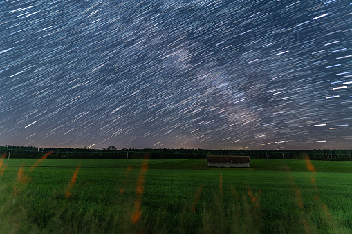 Startrails over a little hut at a farmland at the starry night, beautiful nature and concept for motion of the earth