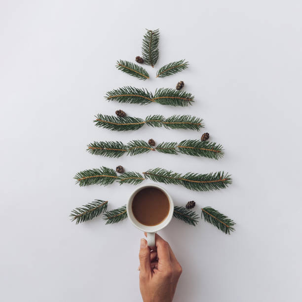Winter modern holiday christmas tree and hand with a cup of hot drink. Minimal trend concept. stock photo