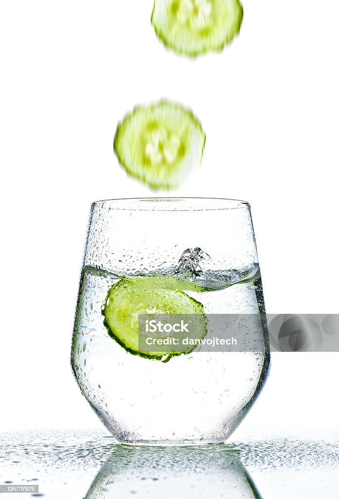 cucumber falling into glass of water cucumber falling into glass of water on white background Clean Stock Photo