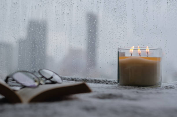 Burning aroma candle puts near by window Burning aroma candle puts near by window that have rain drop in monsoon season with blurred city background. Zen and relax concept. scene scented stock pictures, royalty-free photos & images