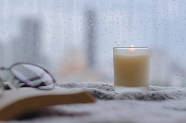 istock Burning aroma candle puts near by window that have rain drop 1340180169