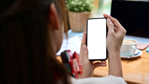 istock Rear view young female using smart phone at office desk. 1340182080