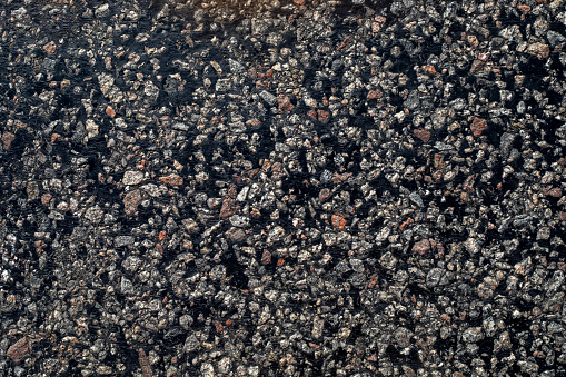 background of the road from black asphalt and multicolored rubble, horizontal