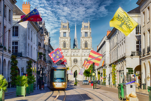 Hermosa calle con tranvía, banderas y catedral gótica en Orleans, Francia photo