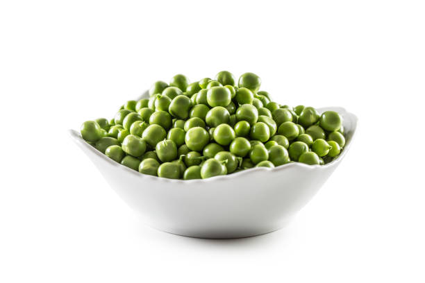 istock Fresh Green peas in white bowl isolated on white background. 1340187455