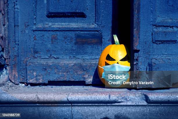 Halloween Background A Naughty Pumpkin Wearing In A Medical Mask Peeking Out From Behind An Old Abandoned Door Stock Photo - Download Image Now