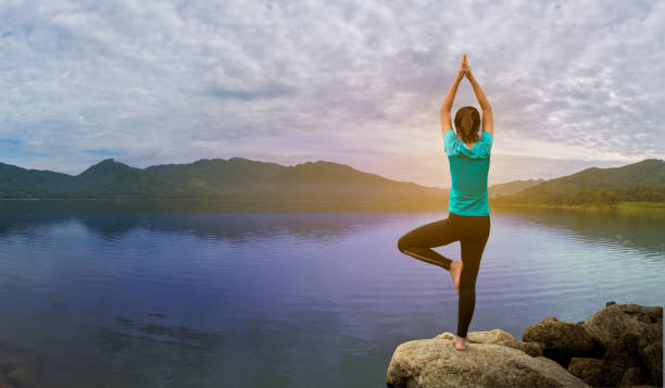 istock Young woman is practicing yoga at mountain lake. 1340188887