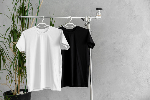 White and black T-shirts on hangers for design presentation, copy space