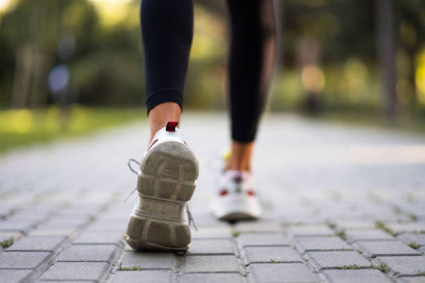 Close-up photo of a shoe of the female runner on a brick road in the park.