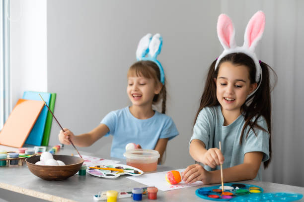istock Happy easter. Two sisters painting Easter eggs. Happy family children preparing for Easter. Cute little child girl wearing bunny ears on Easter day. 1340196776