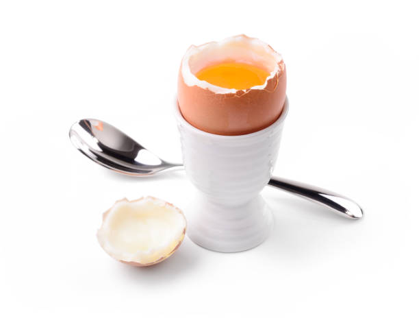 huevo cocido suave con taza de huevo y cuchara aislada sobre fondo blanco, primer plano. - soft boiled fotografías e imágenes de stock
