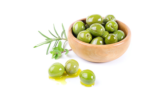 Olives in wooden bowl with extra virgin olive oil and herbs.