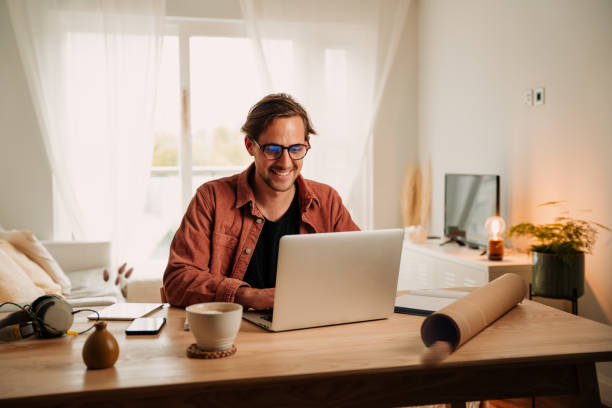Caucasian male working from home typing on laptop finishing project Caucasian male working from home typing on laptop finishing project smiling while being productive. High quality photo man laptop stock pictures, royalty-free photos & images