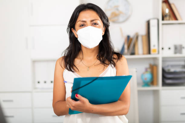 istock Business woman in face mask writing down tasks in office 1340200916