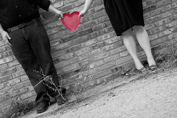 Close-up of young romantic couple is kissing near gray wall on the street. Black and white