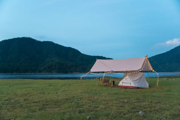 istock Camping with a tent on the grass by the lake 1340207835
