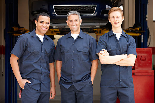 Mechanics at work Three Male mechanics at work standing in workshop uniform stock pictures, royalty-free photos & images
