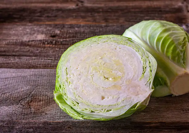 half cabbage on rustic wooden table background. Isolated and closeup view with copy space