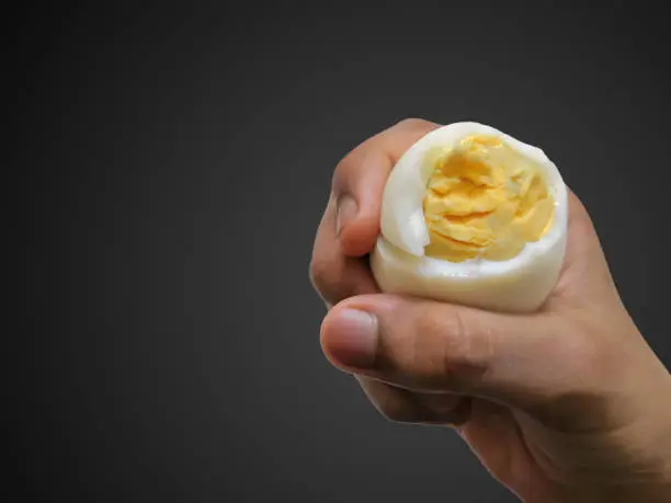 Closeup Image Of Child Holding Sliced Boiled Chicken Egg. Black Isolated Background. Selective Focus