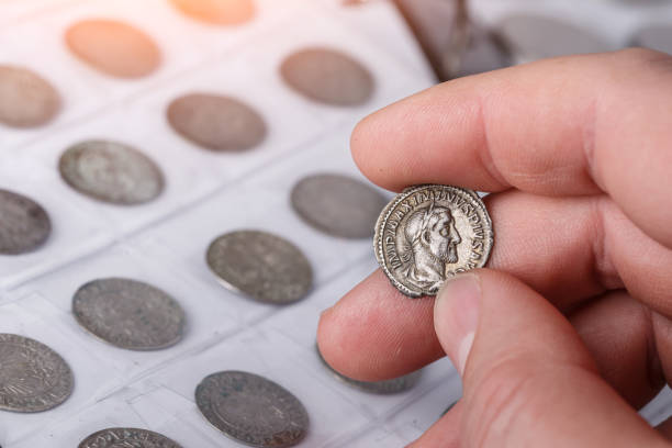 numismatics. old collectible coins made of silver on a wooden table. a collector holds an old coin.ancient coin of the roman empire. - coin collection imagens e fotografias de stock