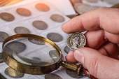 Numismatics. Old collectible coins made of silver on a wooden table. A collector holds an old coin.Ancient coin of the Roman Empire.